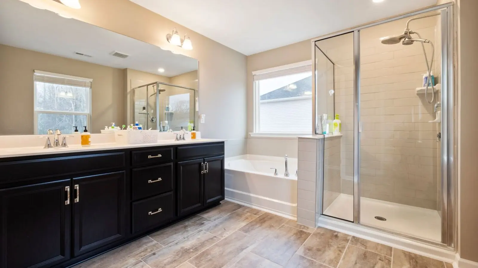 The same bathroom after renovation, with a double vanity, tub and glass shower