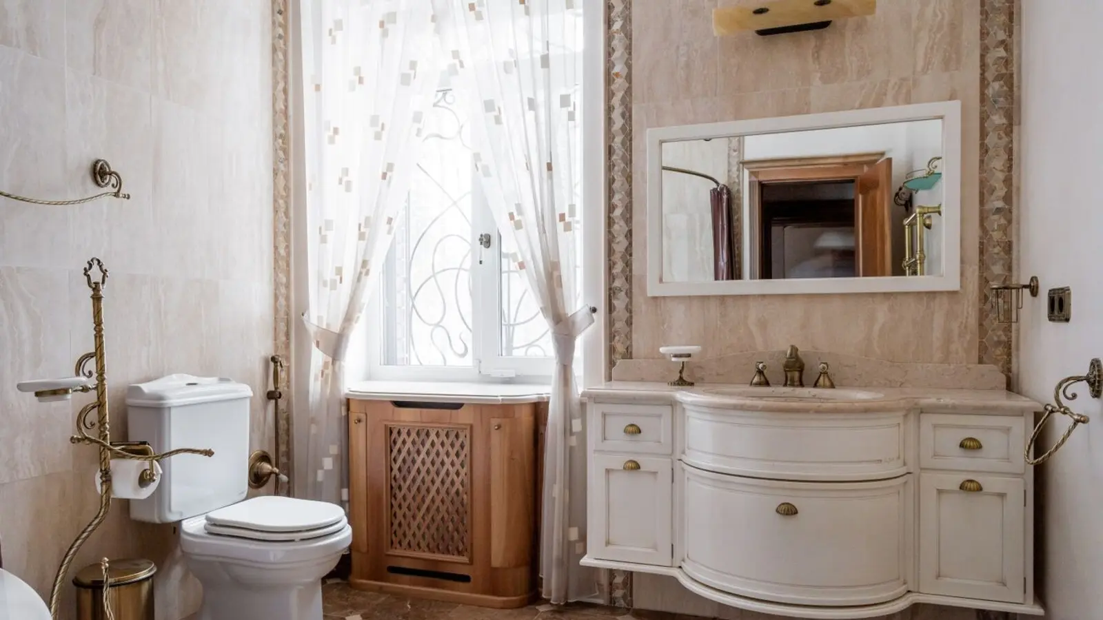 A dated bathroom with ornate tile, a boxed-in radiator and an old vanity