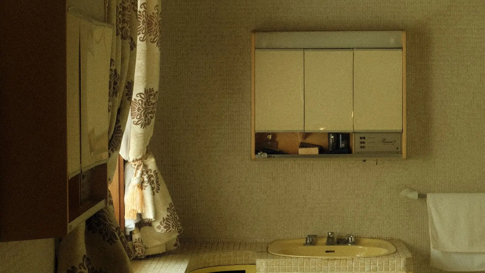 A dated hall bathroom with a yellow sink and a mirrored wall cabinet