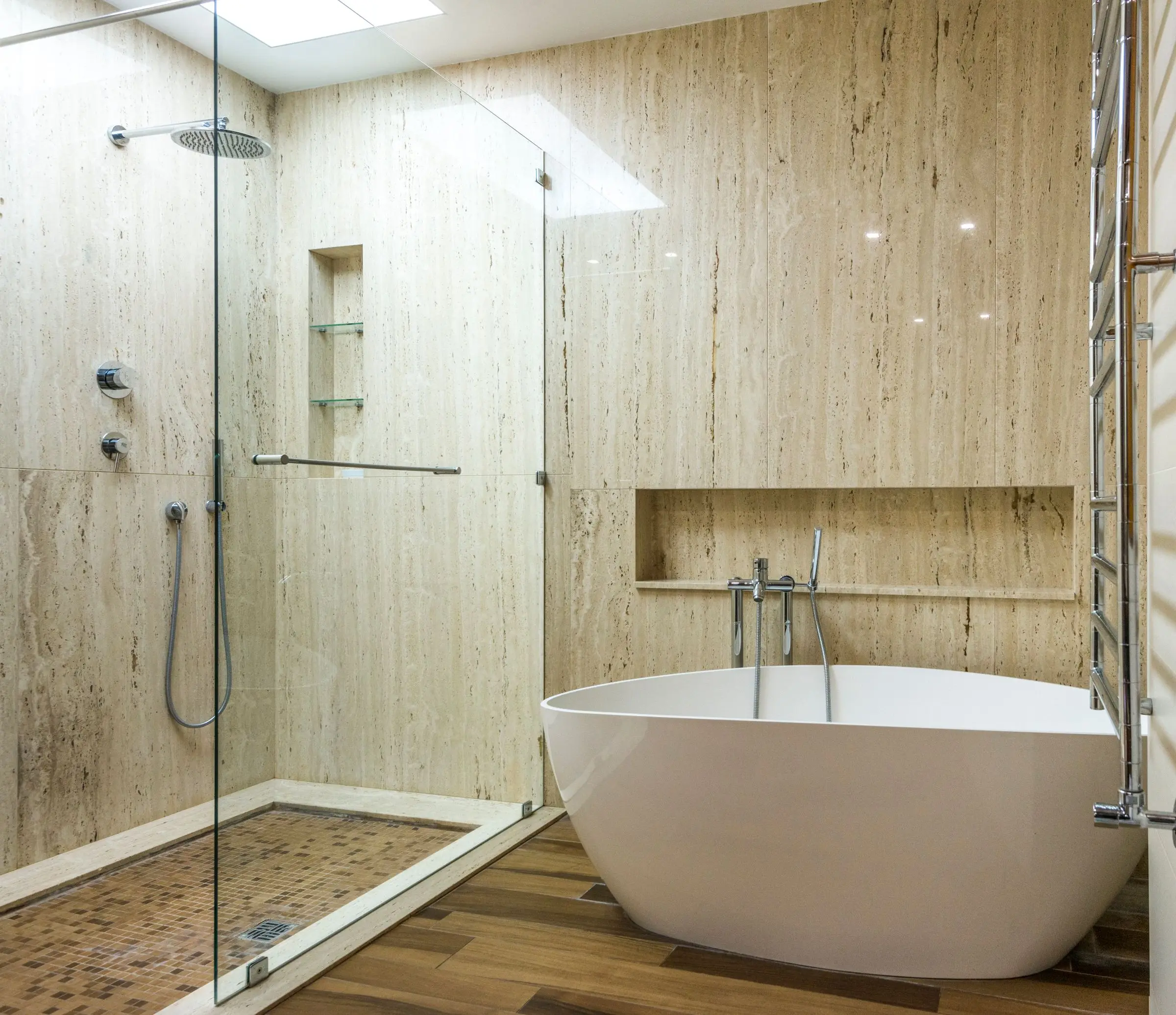 A finished bathroom with a freestanding tub, stone walls and a glass shower